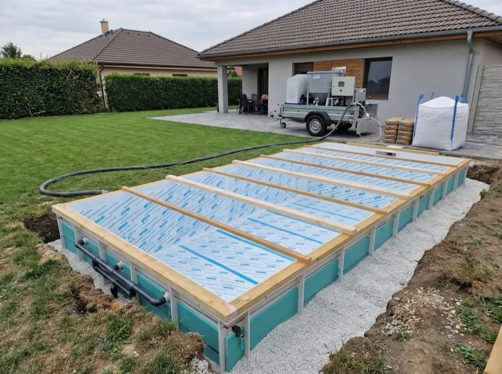 Mobile Mischanlage auf dem Anhänger vor dem Haus, Schlauch bis zur Baugrube – kein Betonfahrzeug im Garten